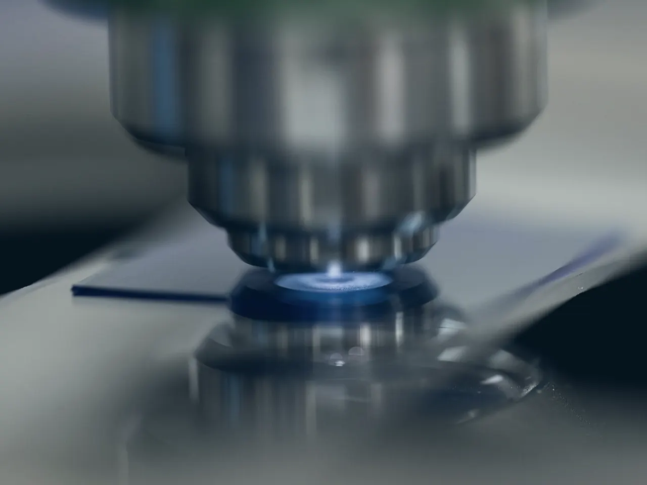 Microscope objective lit in blue above a glass slide